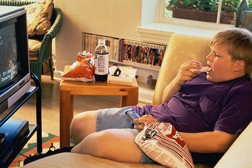 Boy (10-11) eating junk food while watching televisiongett images stock